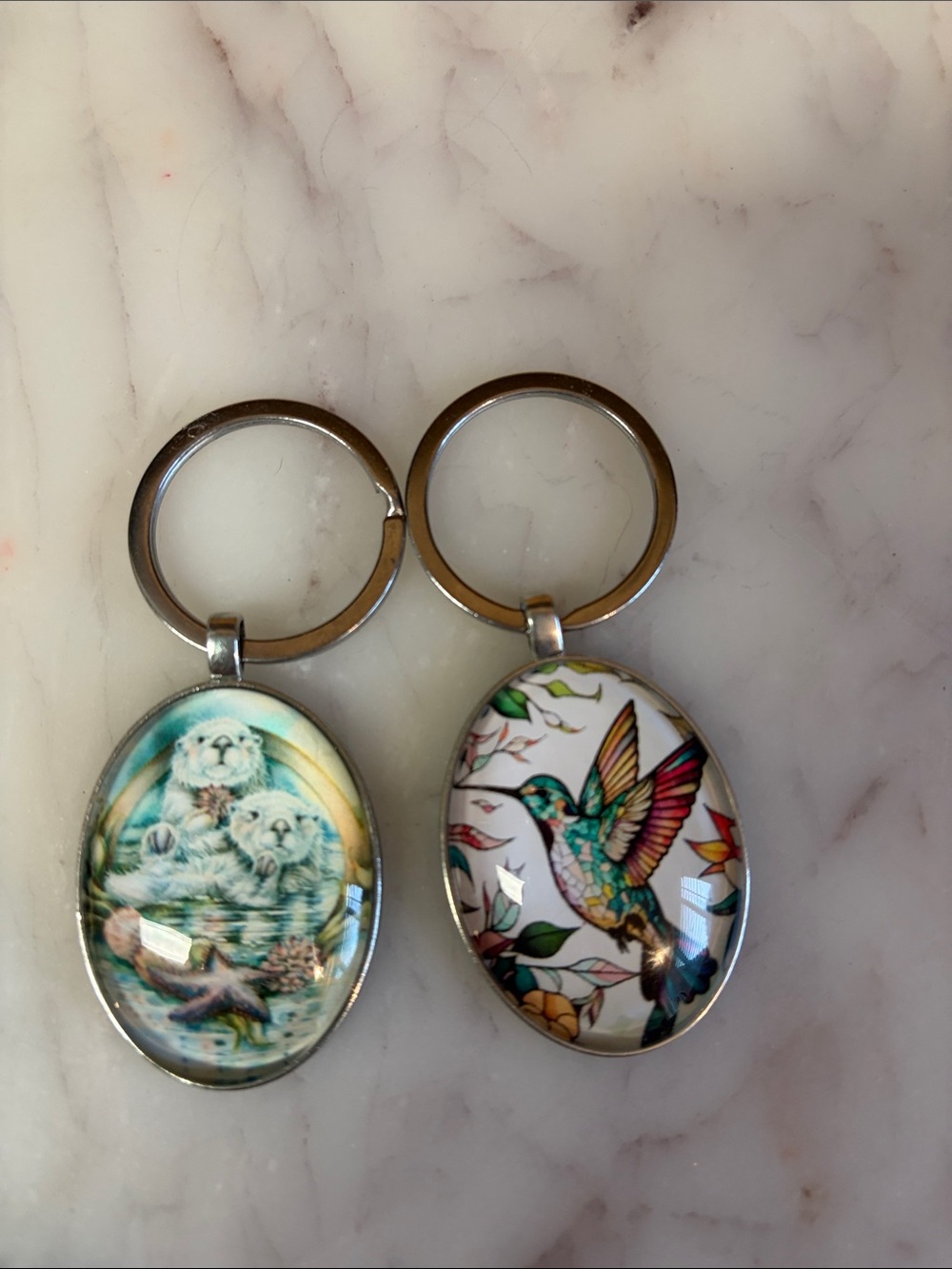 Silver Oval Hummingbird and Sea Otter Keychain Duo - White and Multicolor